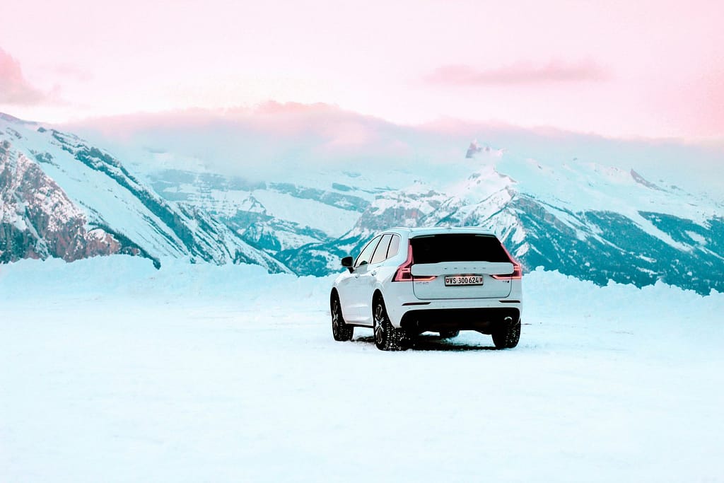 White Luxury SUV Driving Through Snowy Mountains