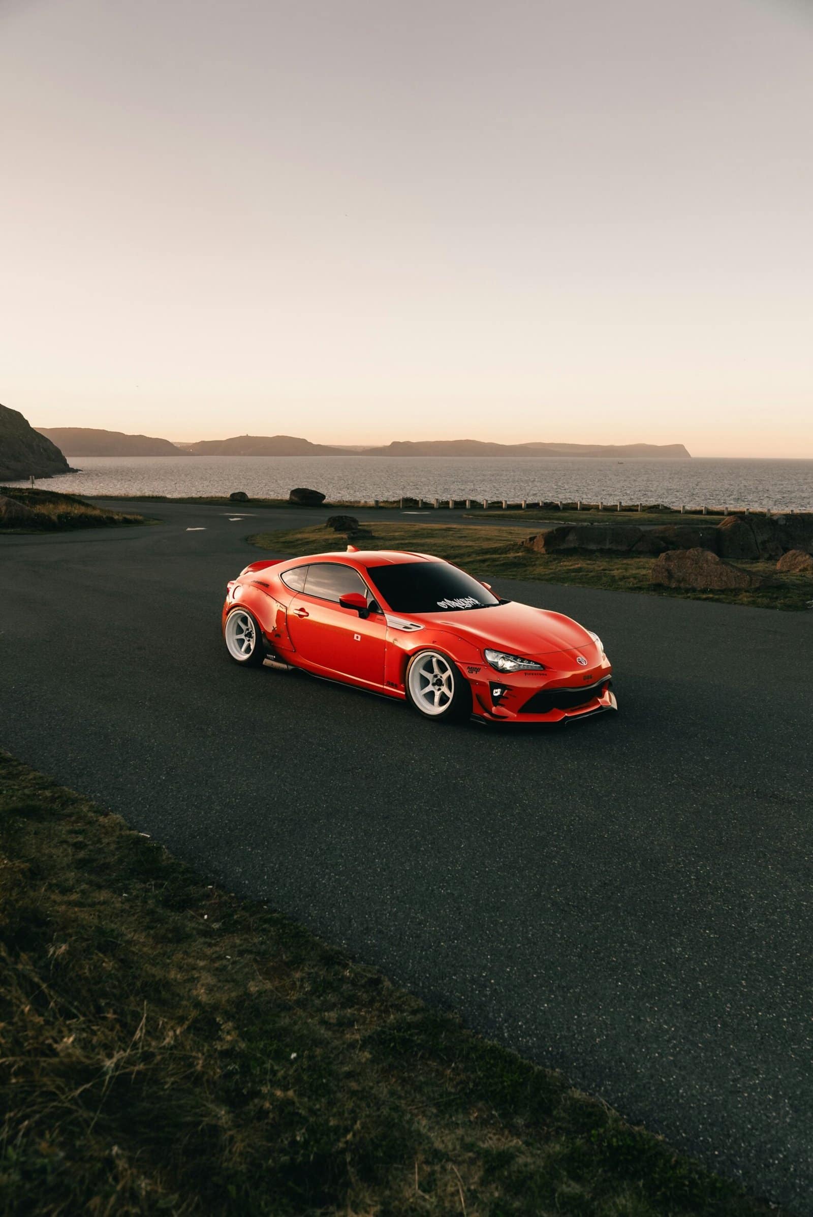 Red Sports Car on Coastal Highway at Sunset