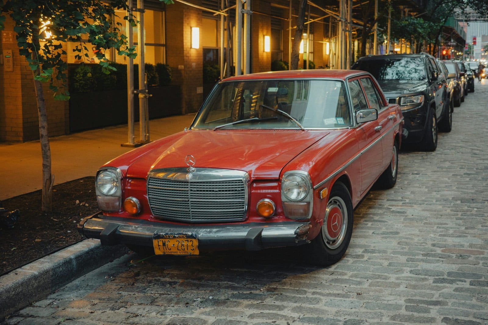 Red Classic Car Parked on Cobblestone Street at Dusk