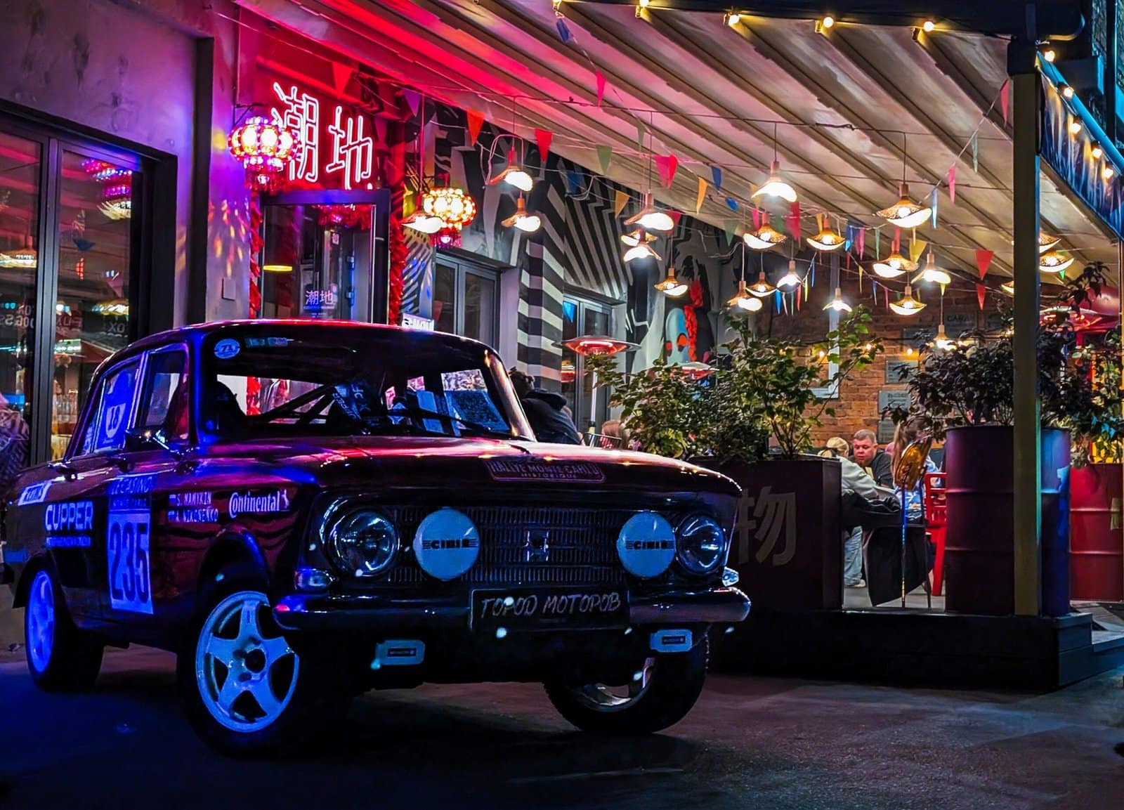 Classic Car Cruising Down a Neon Lit Street at Night