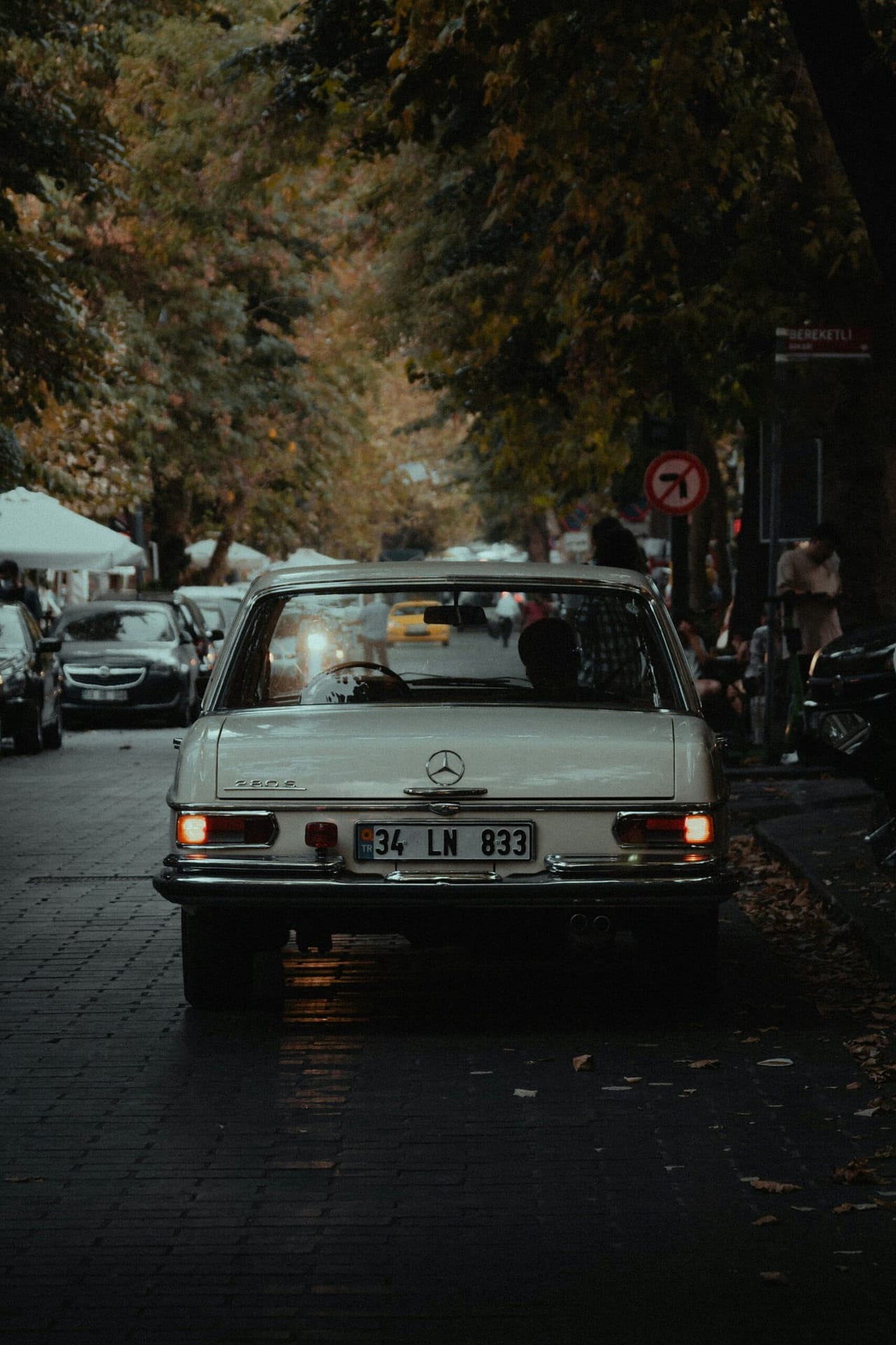 White Vintage Car Driving Through Autumn Forest Road