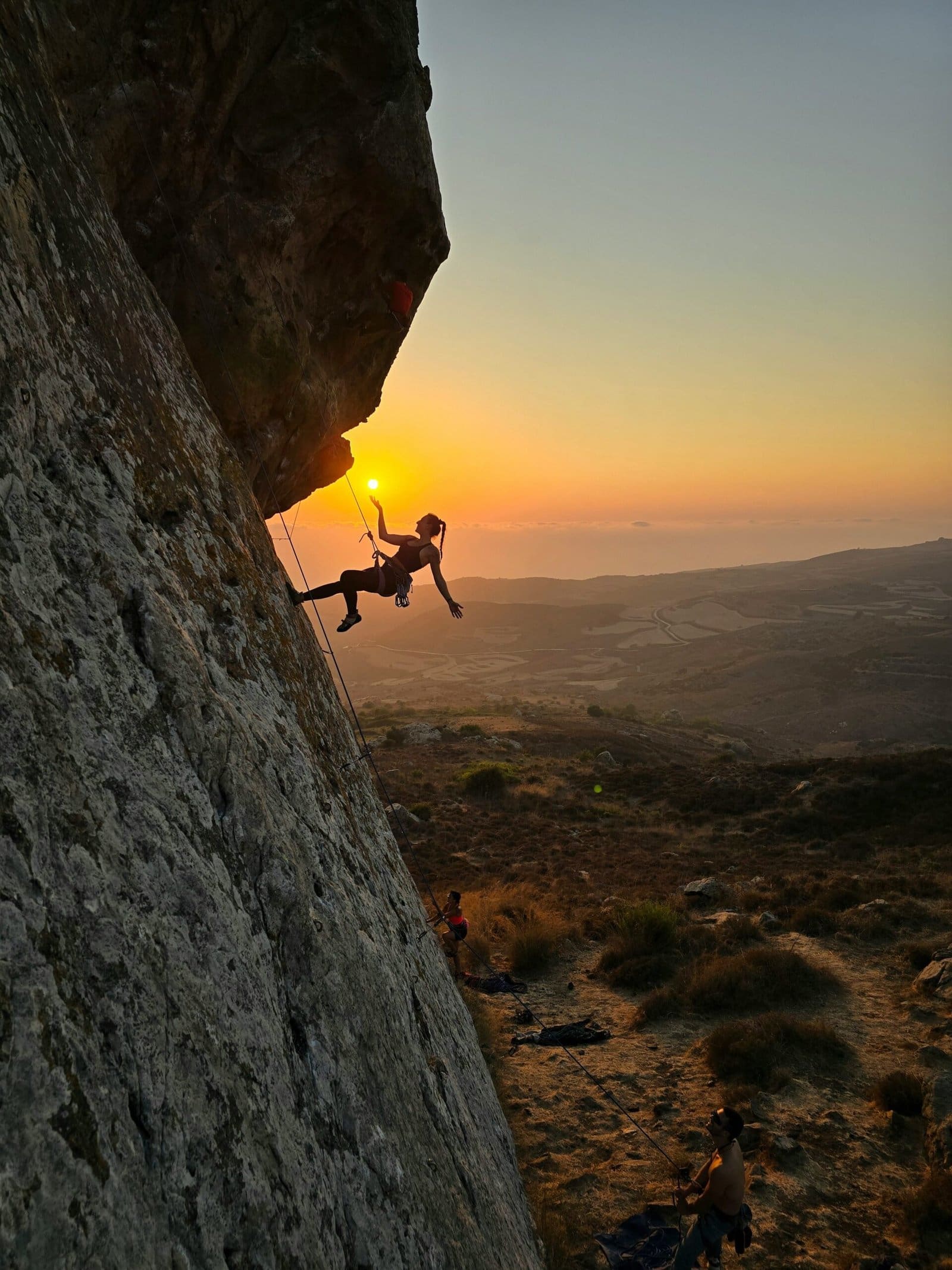 Rock Climber Scaling Golden Cliff Face At Sunset