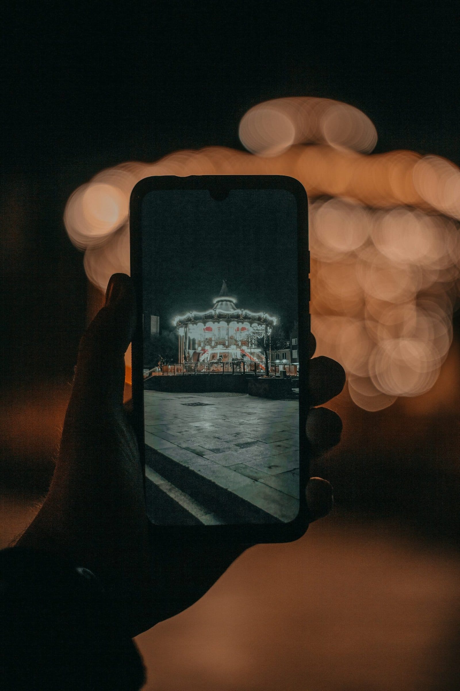 Hand Holding a Smartphone Against Glowing City Bokeh