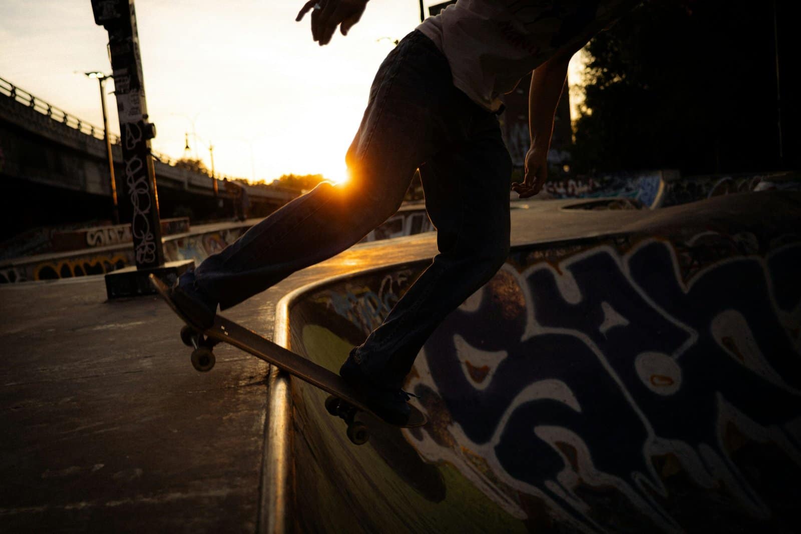 Skateboarder Performing Trick Against Graffiti Wall at Sunset