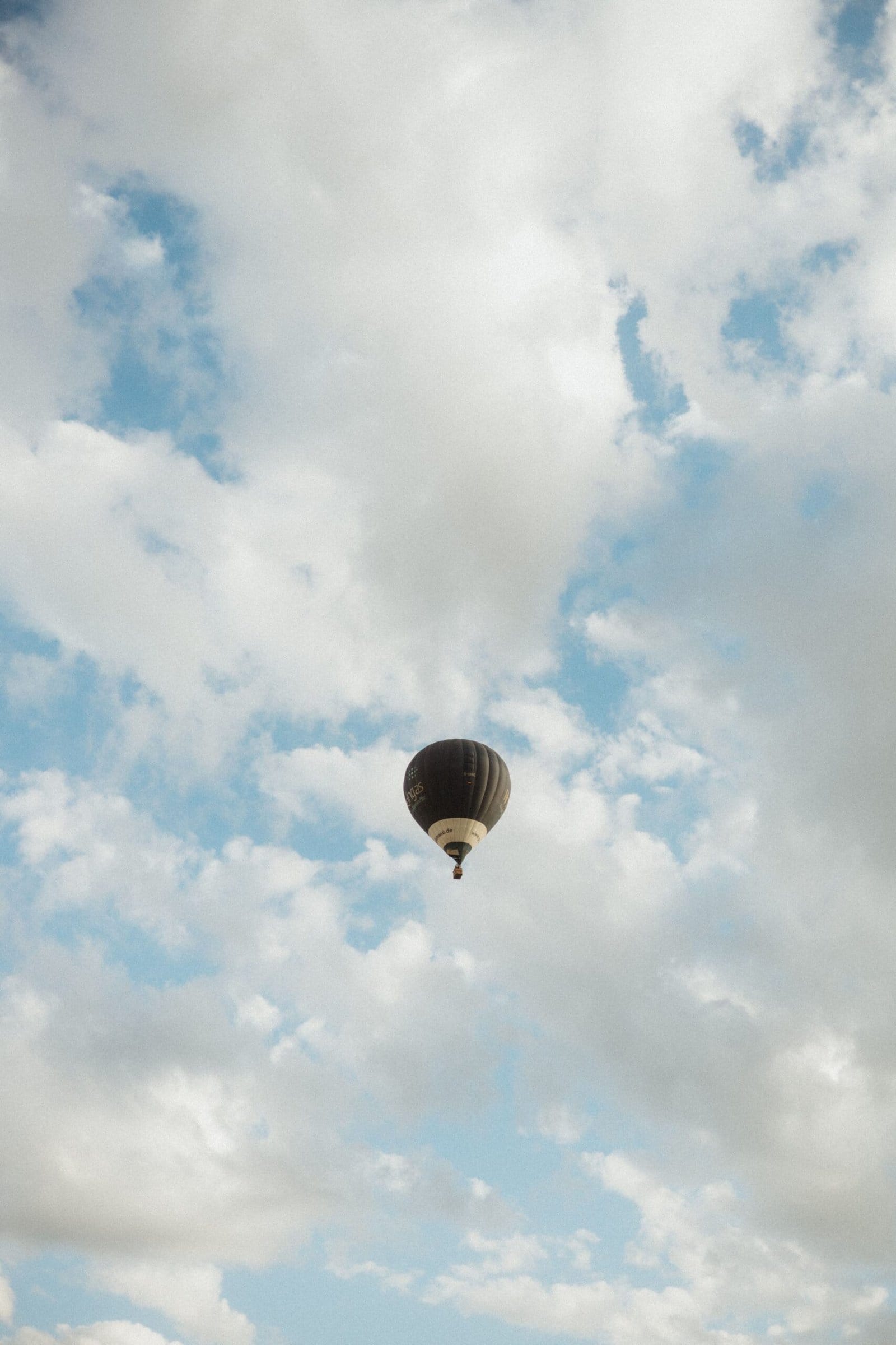 Lone Hot Air Balloon Floating Amidst Fluffy Clouds