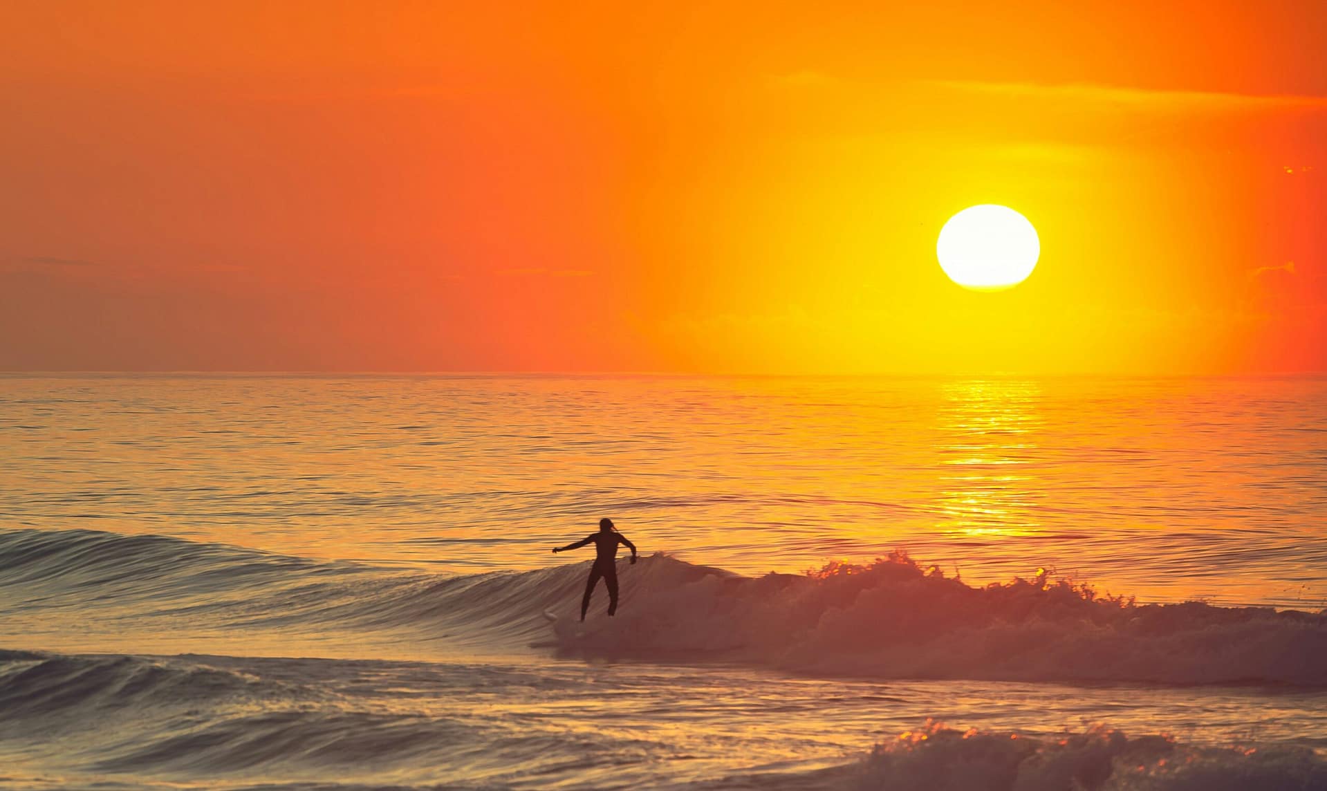Surfer Riding a Giant Ocean Wave at Sunset