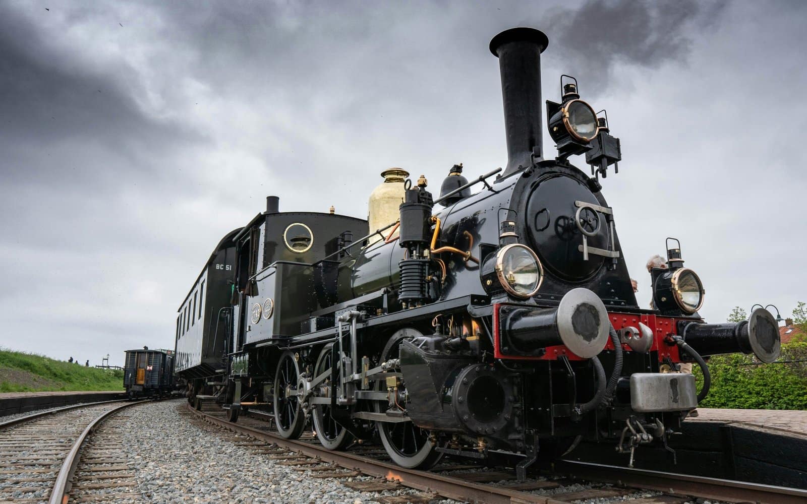 Black Steam Train on Railway Tracks Under Cloudy Sky