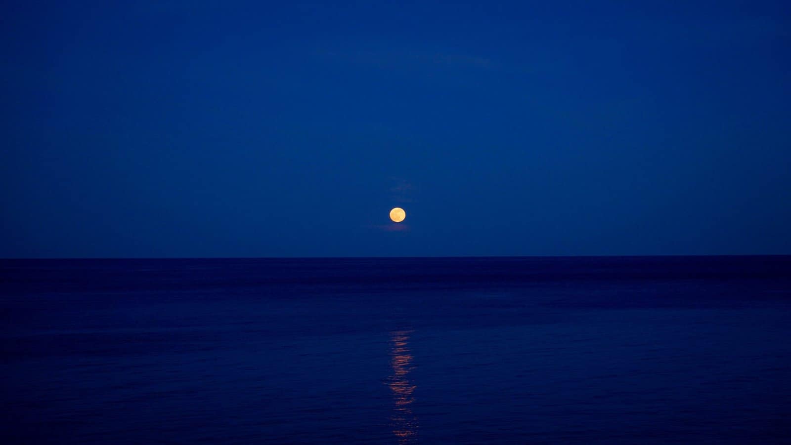 Full Moon Rising Over Silent Ocean Horizon