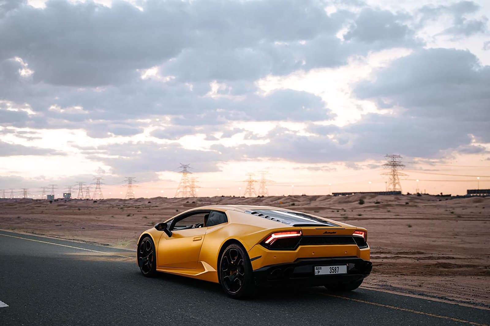Yellow Sports Car Speeding Along Desert Road at Sunset