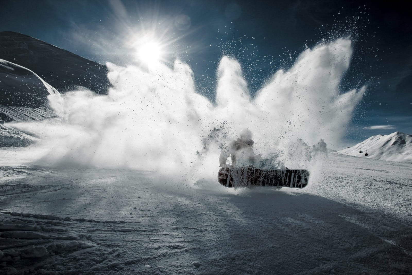 Snowboarder Jumping Over a Powder Mountain Peak