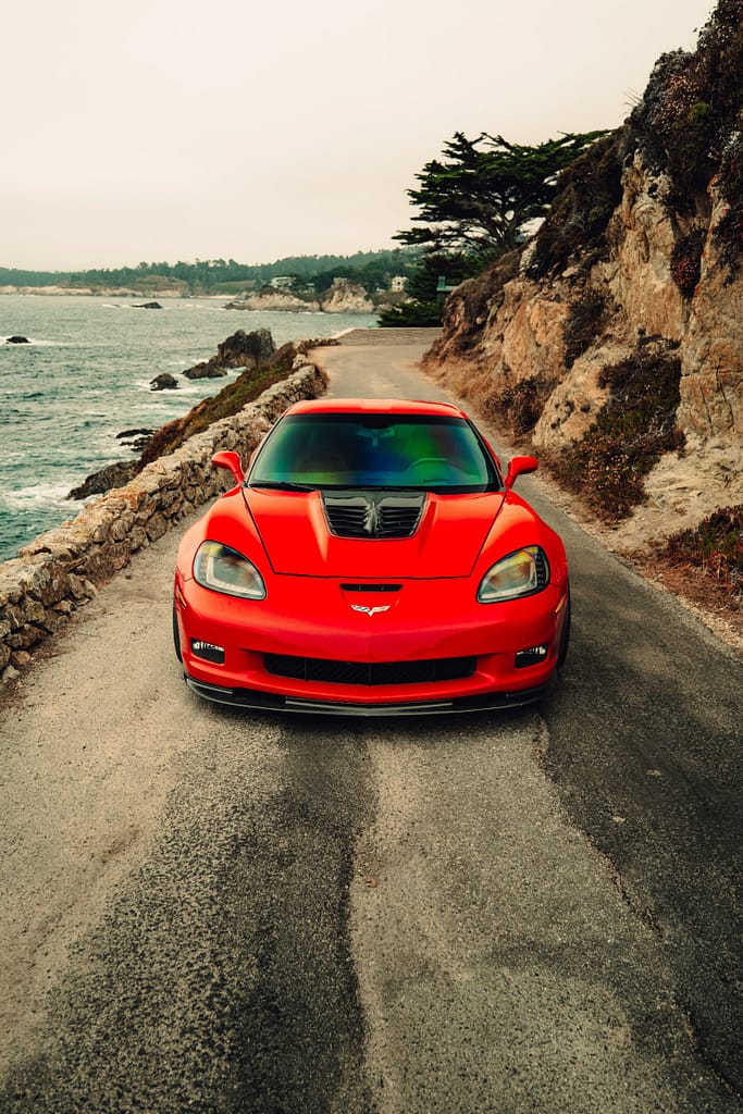 Red Sports Car Racing Along a Coastal Highway